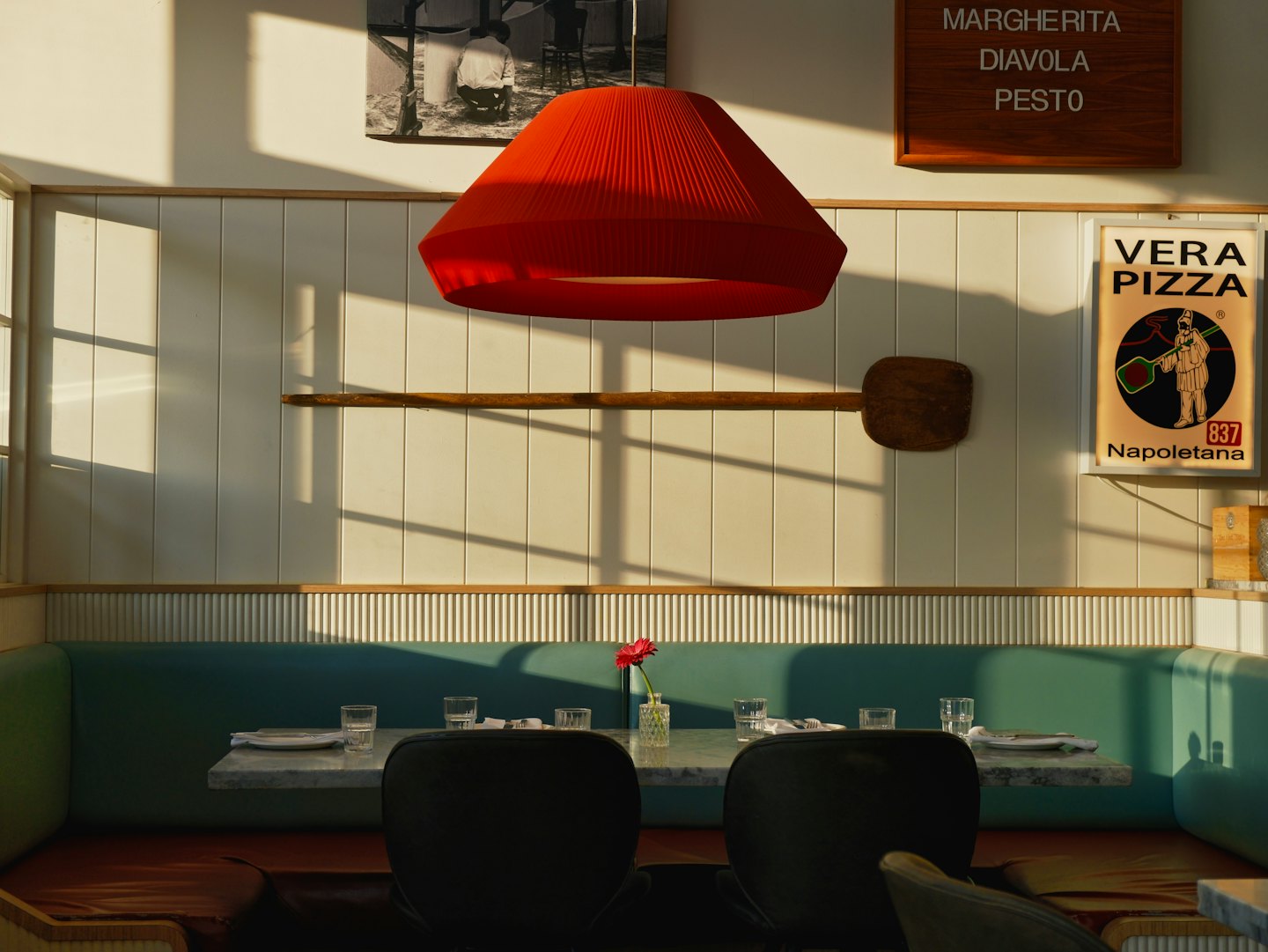 Restaurant interior with teal booth and sunlit tables.