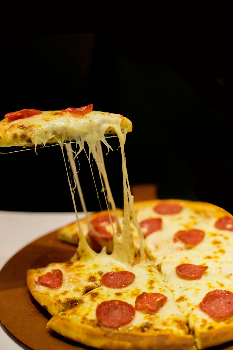Cheese stretching from a slice of pepperoni pizza.