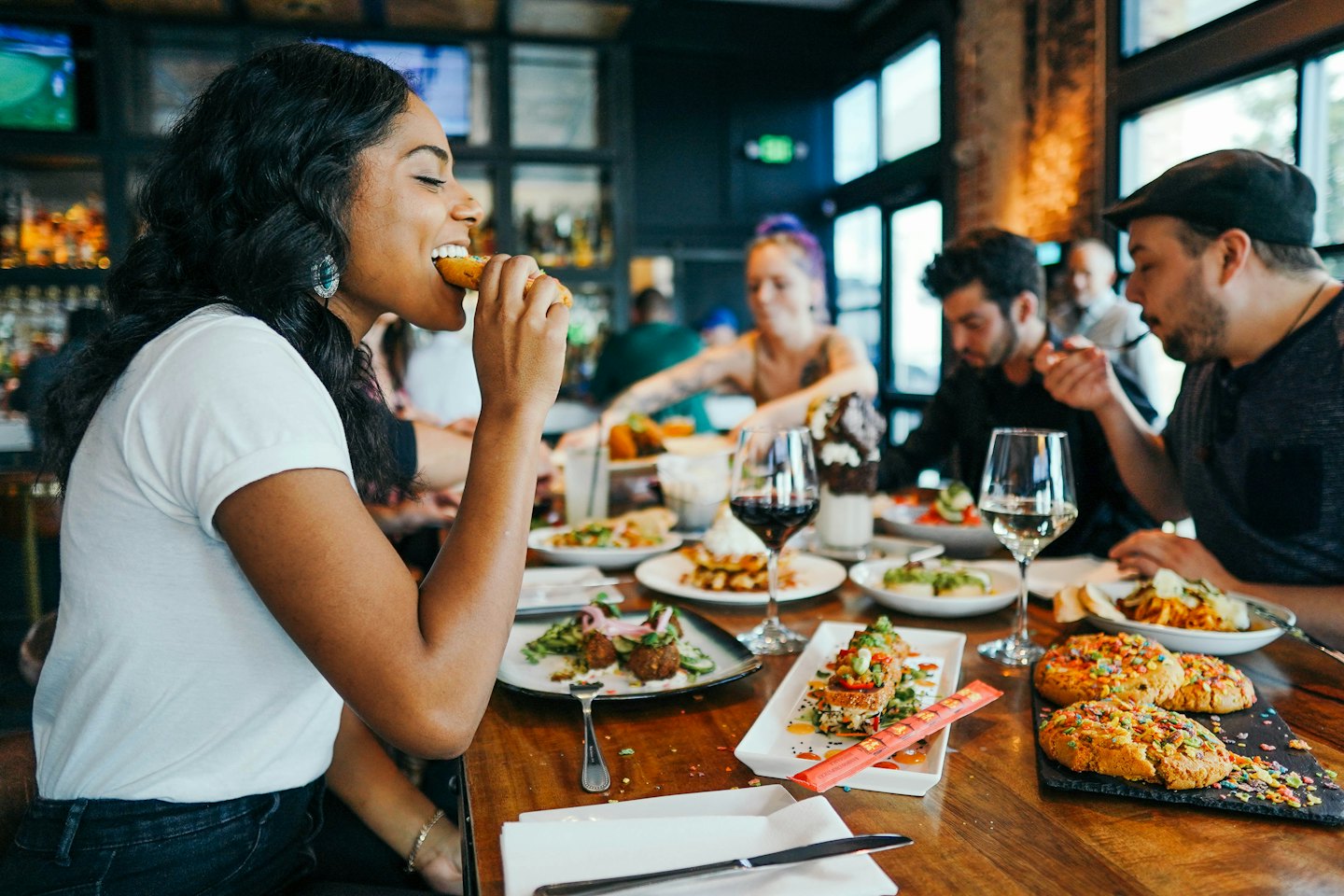 Friends share food and drinks at a restaurant table.