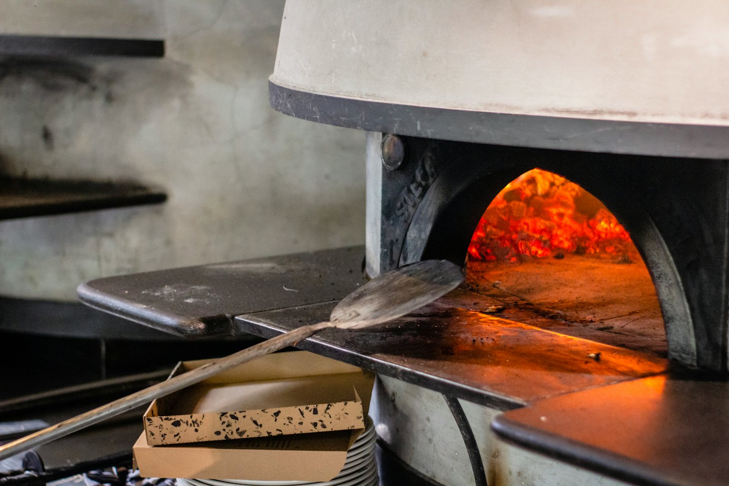 Wood-fired pizza oven with flames and pizza peel.