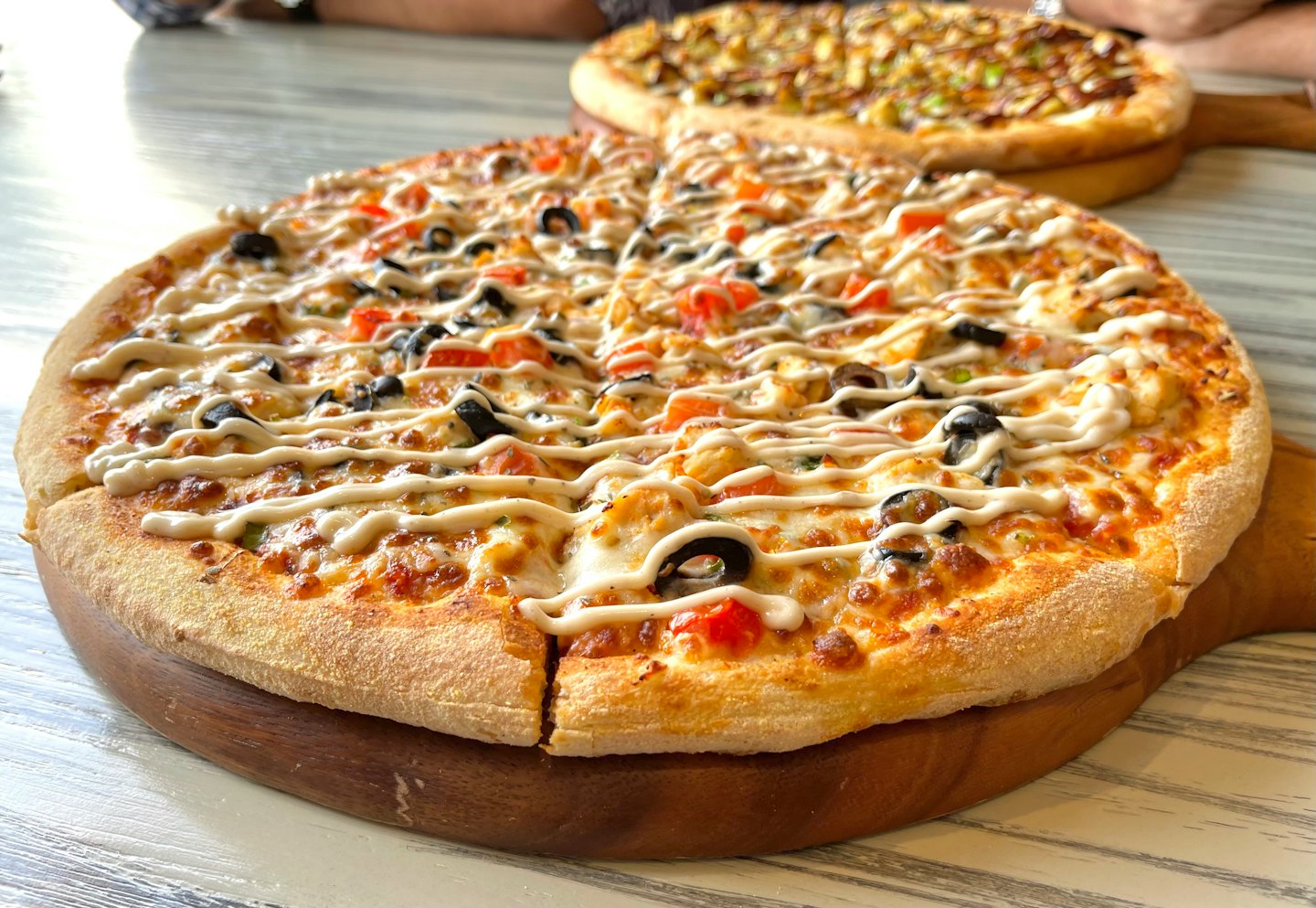 Two freshly baked pizzas on wooden boards on a table.